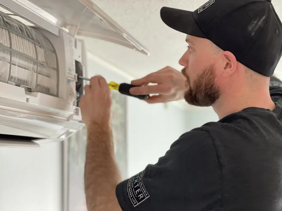 Installer tightening the wiring terminals inside a wall-mounted mini split indoor unit, one of the steps in easy install DIY multi zone mini split systems